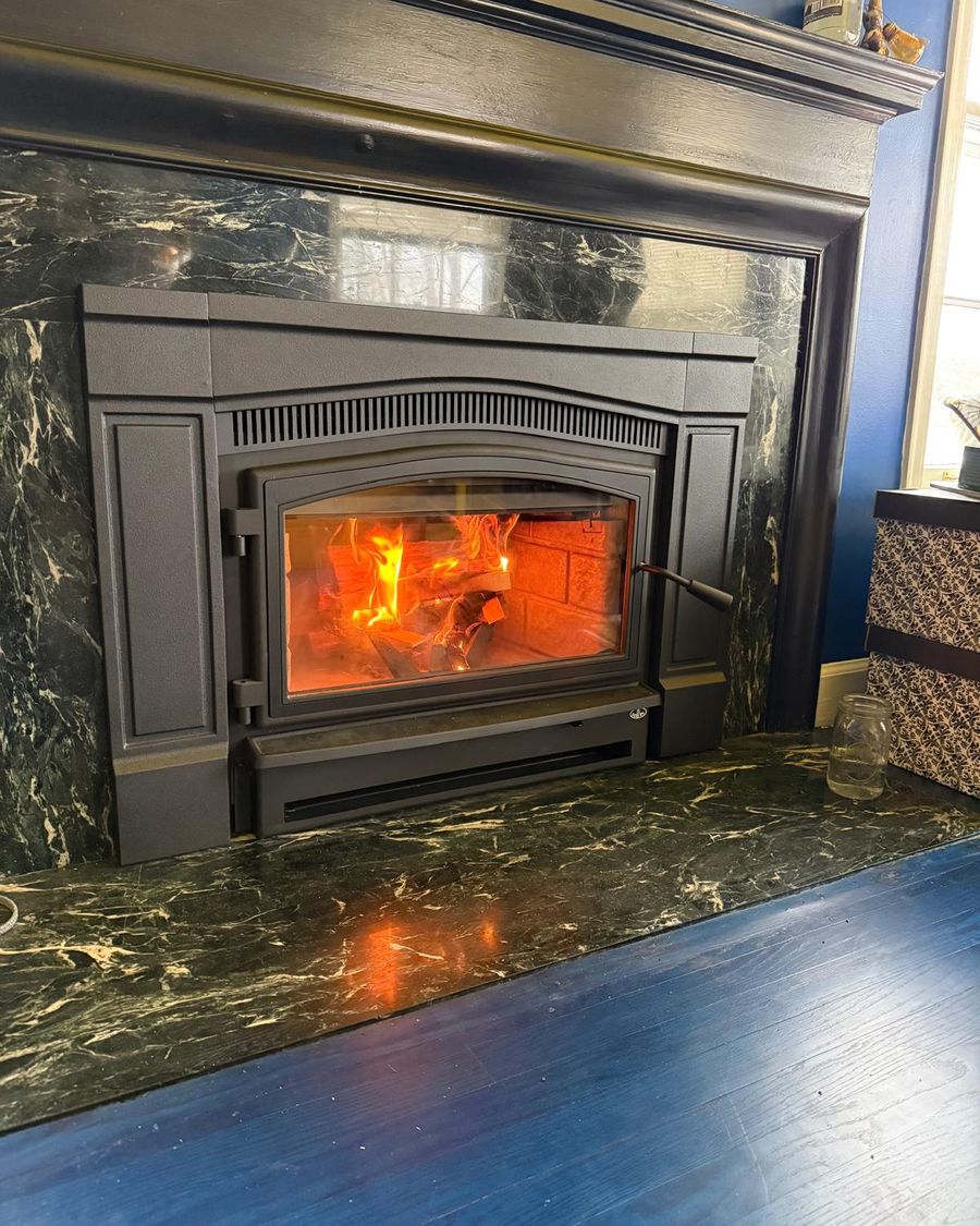 Wood-burning fireplace insert with a bright fire in a green marble surround