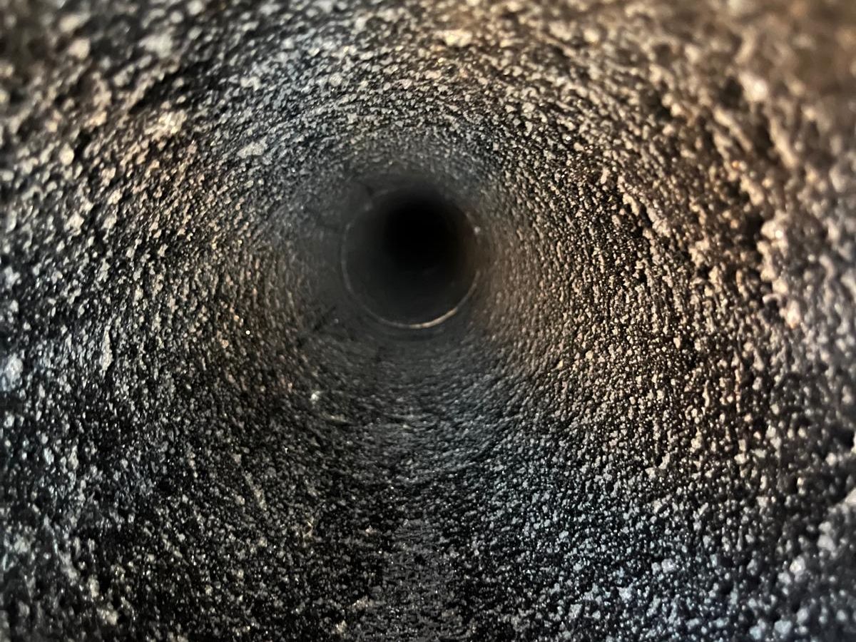 Round flue coated in rough, bubbly creosote