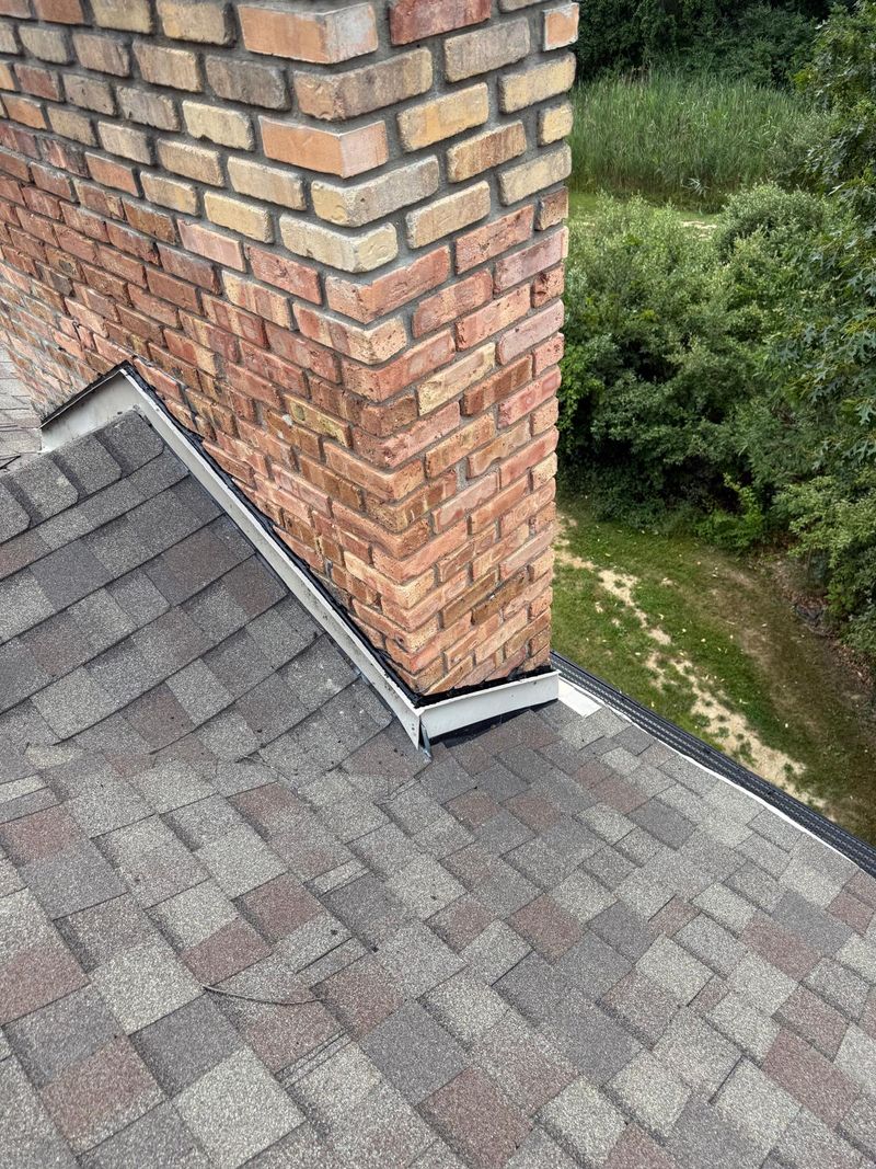 Chimney corner with its beige step flashing sealed against the brick