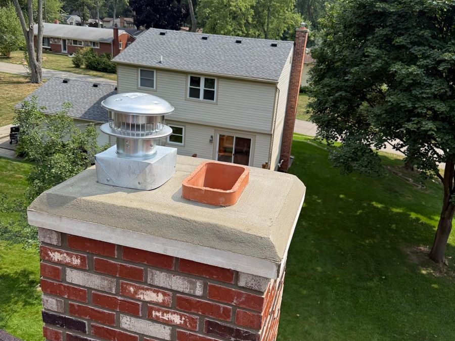 Rebuilt red brick chimney with a new concrete crown with an overhanging drip edge and a new metal cap